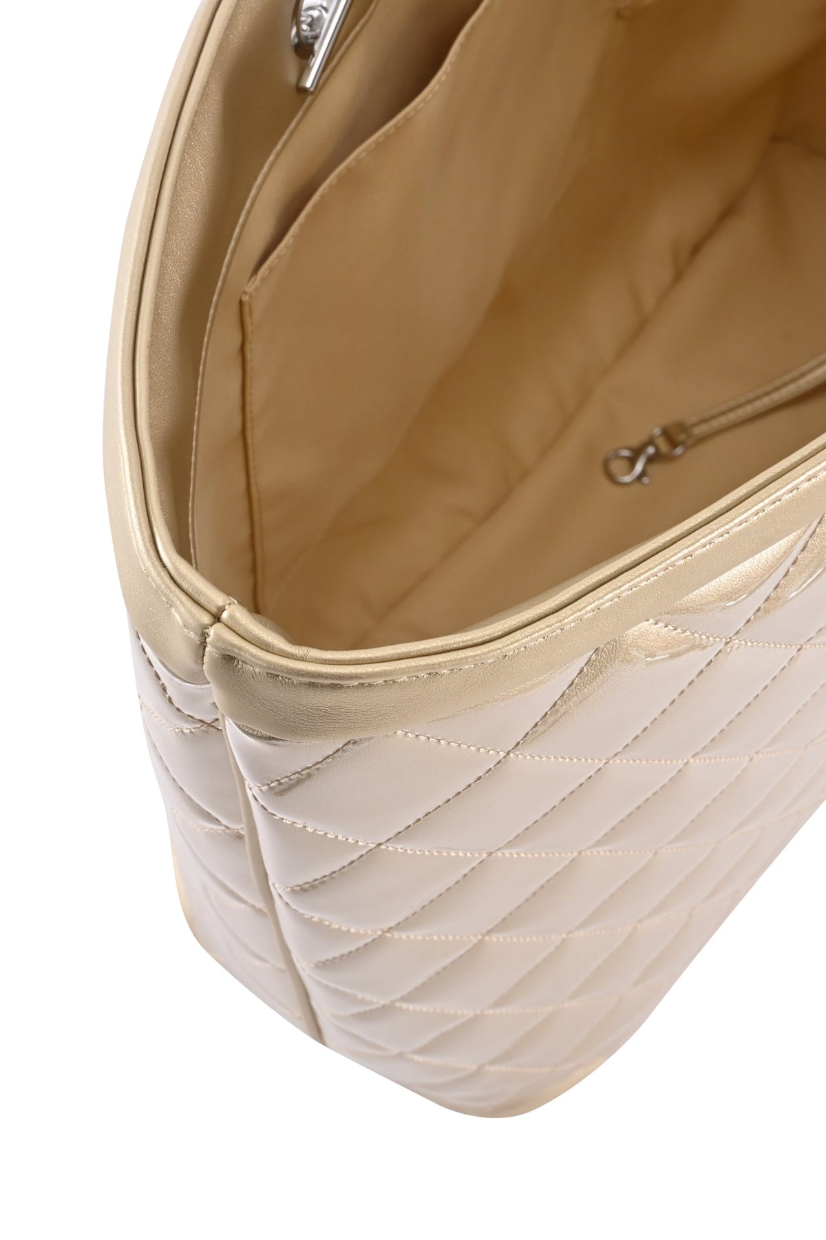 The DANNI TOTE BAG - GOLD by I.AM.GIA is a beige quilted handbag with a spacious interior, featuring a small inner pocket and a secure metal clasp. Its light beige, smooth lining complements the elegant chain link straps. The image shows the bag from above at an angle.