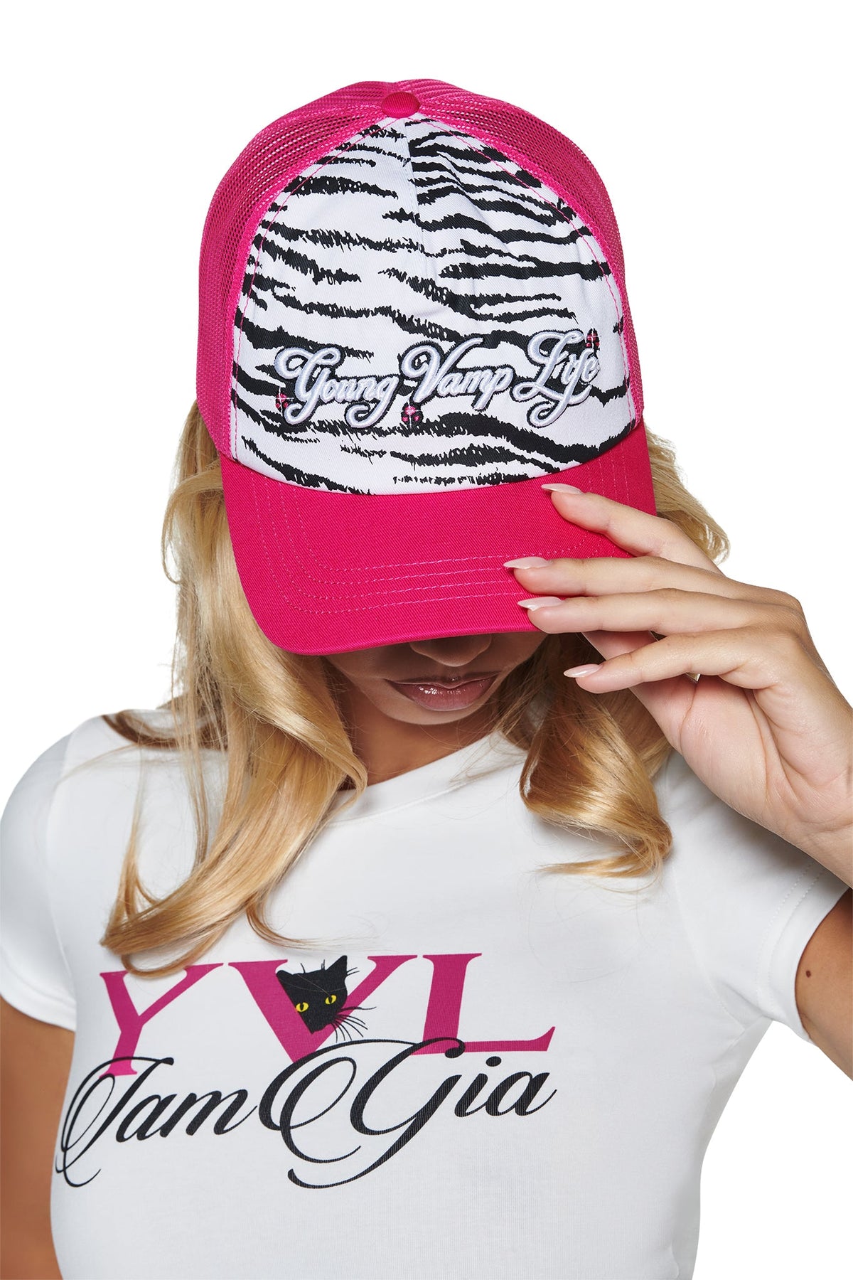 Person wearing a bright pink YVL TRUCKER HAT with a white and black zebra print front panel featuring the embroidered text “Young Vamp Life.”