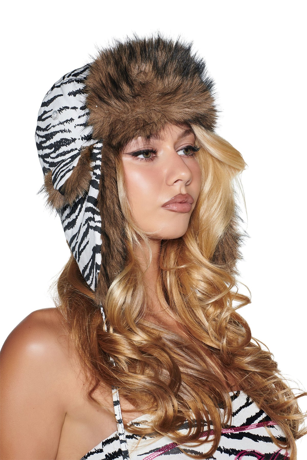 A woman wears an I.AM.GIA YVL FUR TRAPPER HAT - ZEBRA, a zebra canvas trapper hat with brown faux fur trim.