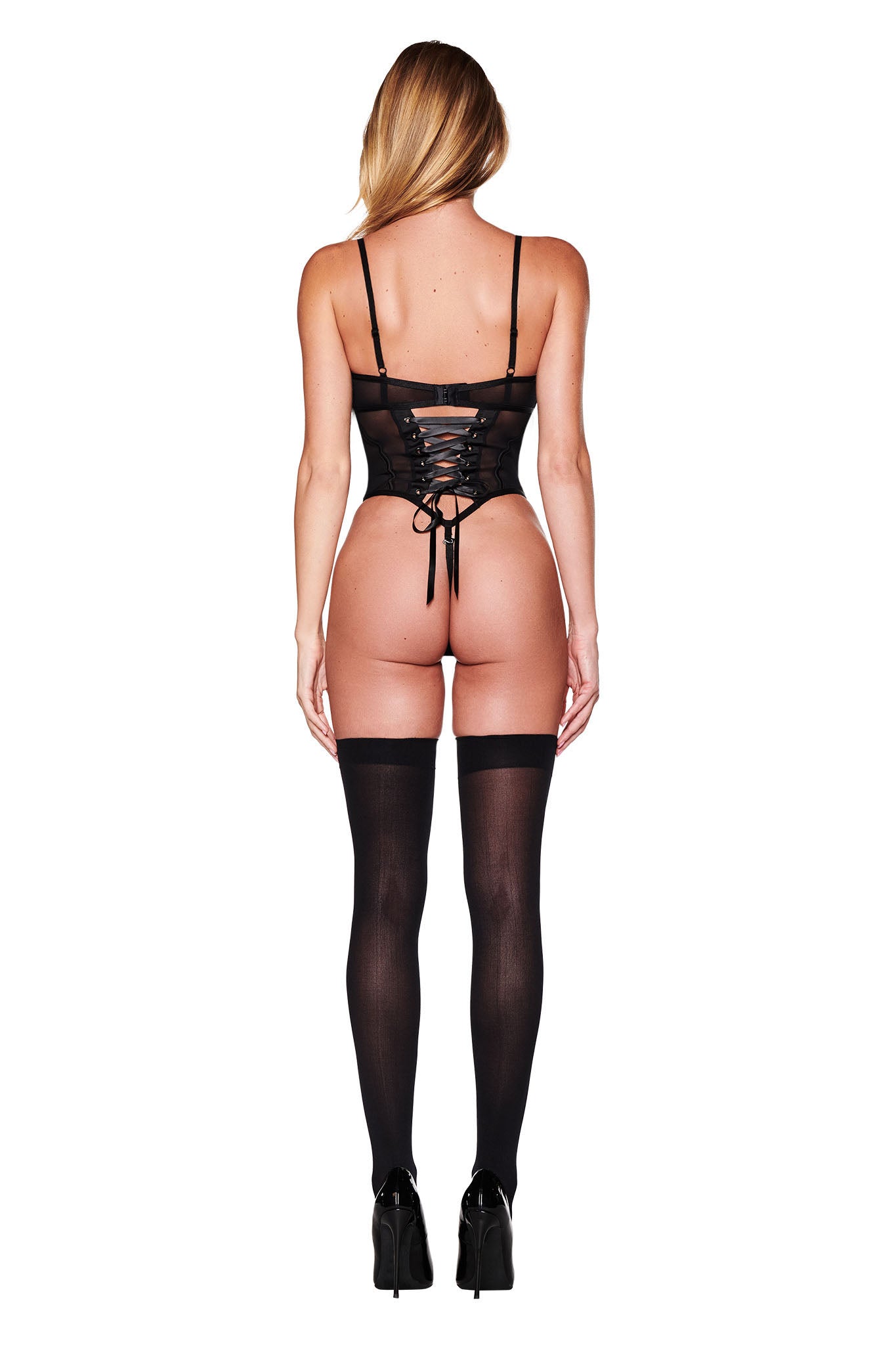 In front of a white background, a person exudes the captivating charm of a retro vixen wearing the JACQUELINE BODYSUIT in black by I.AM.GIA, accompanied by sheer stockings and high heels. The dramatic elegance of the ensemble is accentuated, highlighted by corset boning details.
