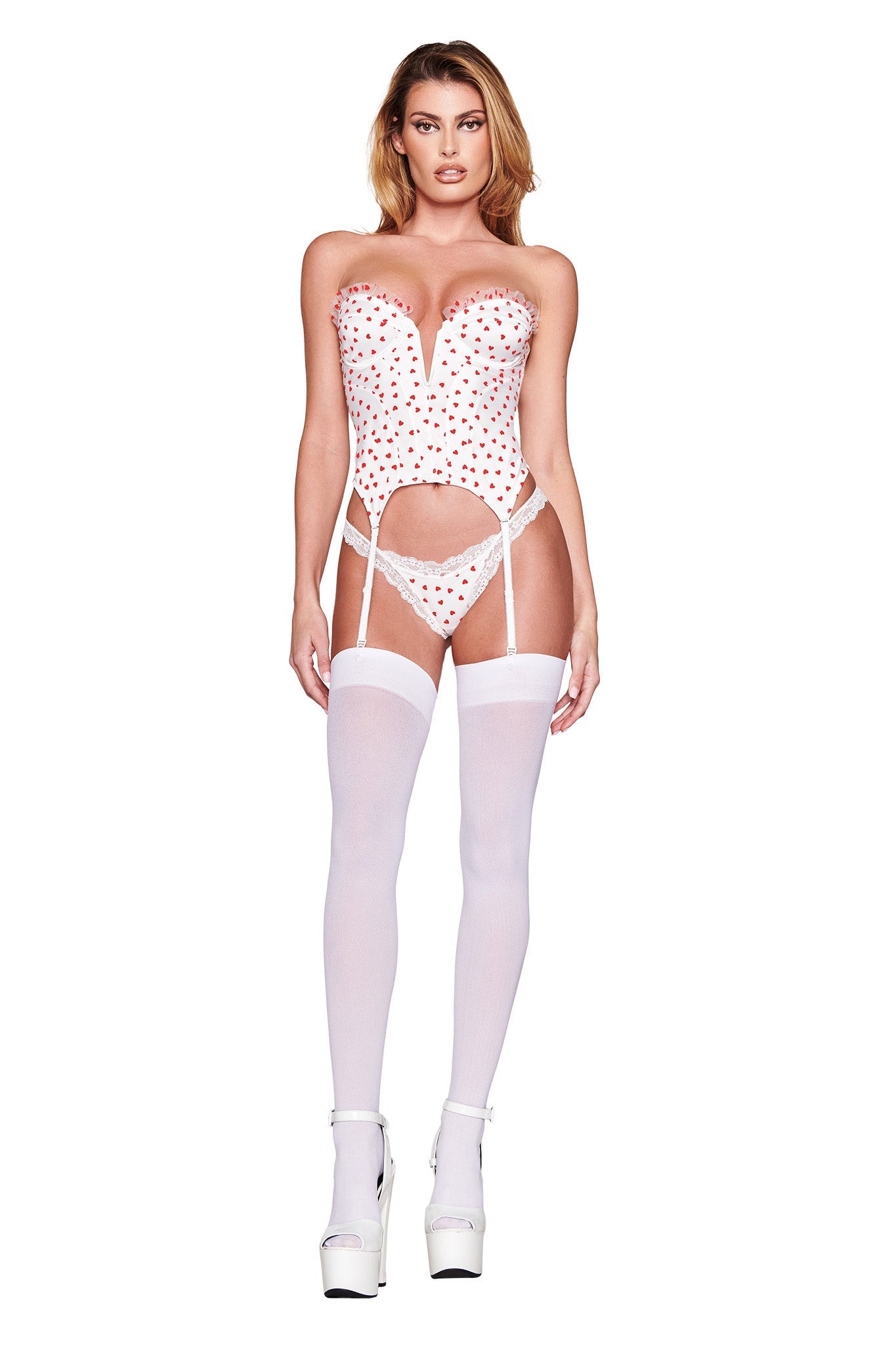 A person wears the I.AM.GIA Pamela Set - White: Heartbeat, featuring a polka-dot lingerie set with a vintage-inspired sweetheart neckline bustier, white stockings, platform heels, and removable garter straps. It's styled with a strapless top against a plain white background.