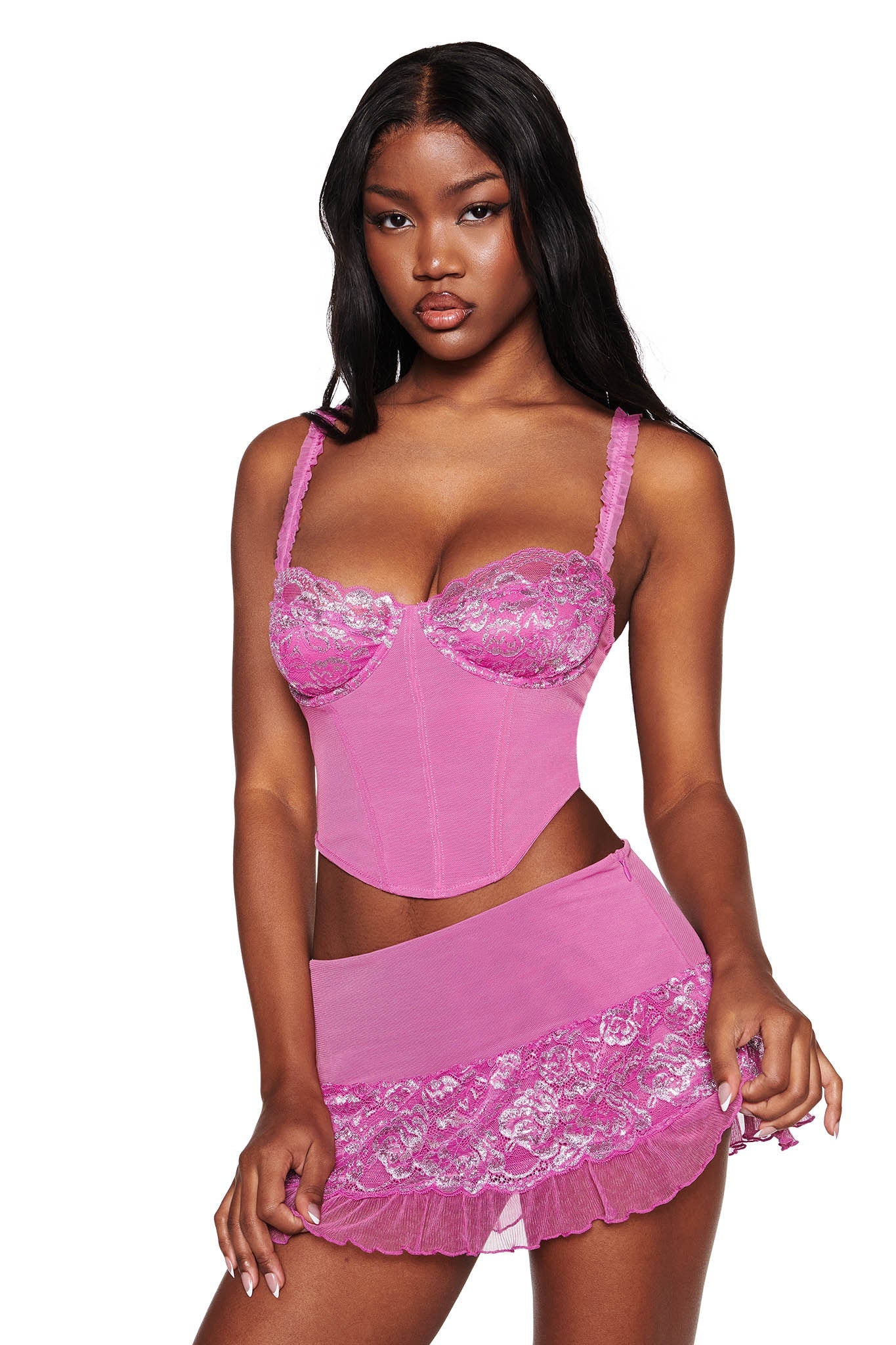 A person models the NYSSA 2.0 METALLIC BUSTIER SET - PINK by I.AM.GIA, showcasing its power mesh bodice with floral lace details and thin straps. They exude elegance against a white background.