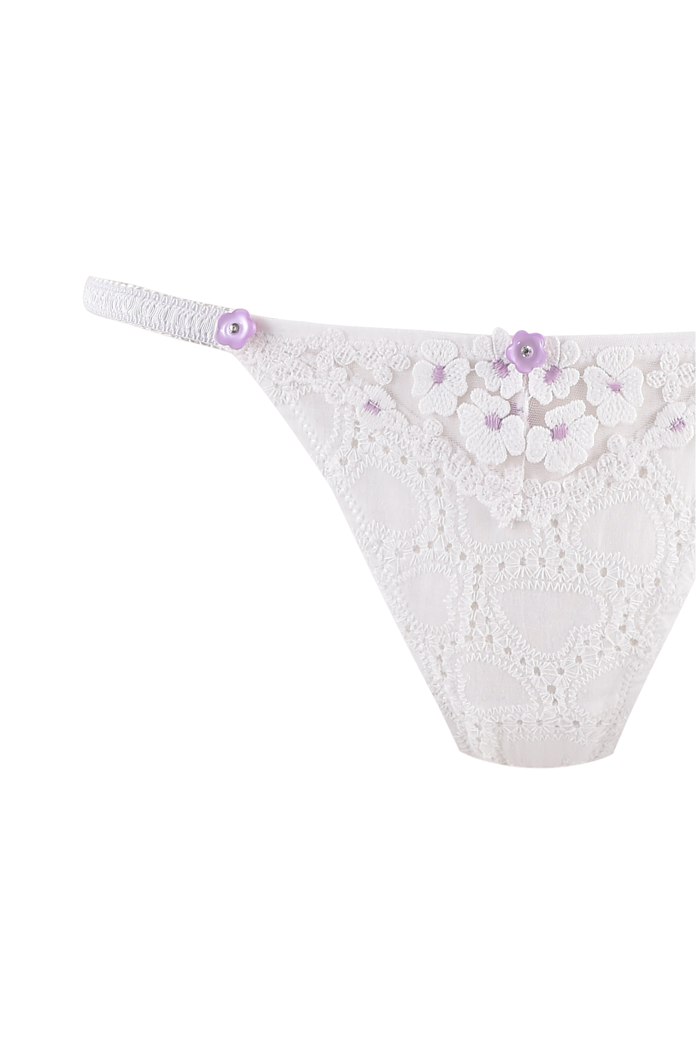 A close-up of the ELLA BUSTIER SET - WHITE by I.AM.GIA, featuring white lace with sheer floral tulle details and small purple flower accents on the waistband and front.