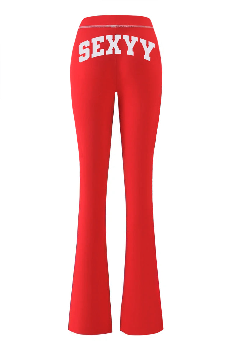 The I.AM.GIA X SEXYY RED BLARE TRACKPANT in bright red is shown from the back, featuring a low-rise waist and bold white "SEXY Y" lettering across the waistband.