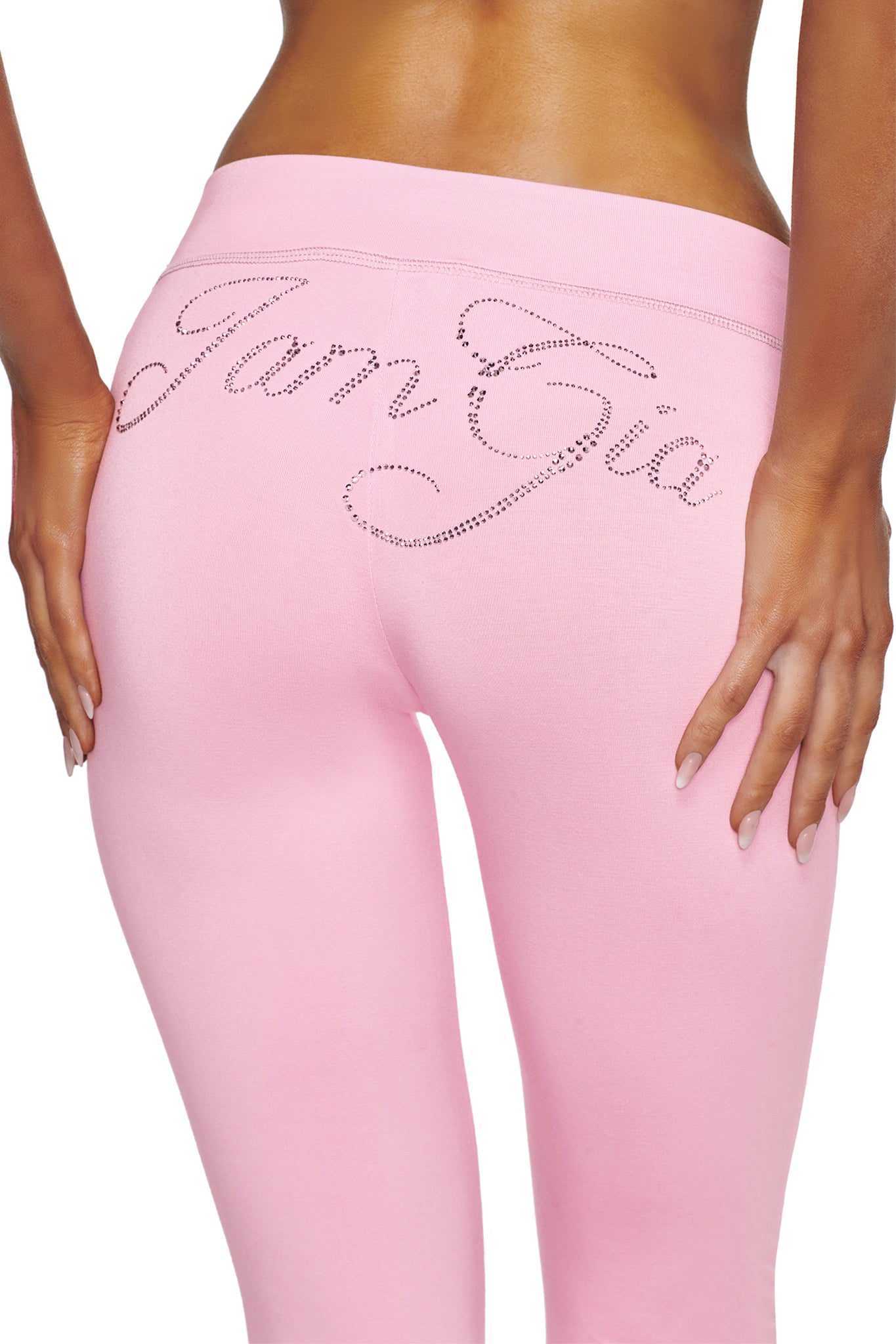 A person wearing the I.AM.GIA BLARE LOW RISE DIAMONTE CAPRI in baby pink, with the sparkling diamante I.AM.GIA logo featured across the back. The image highlights their lower back and upper legs, emphasizing the shimmering brand detail.