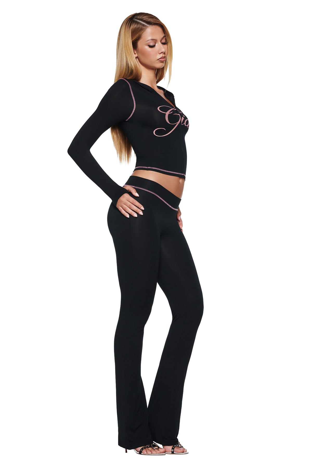 A woman wearing a black BLARE HOODIE - BLACK with pink contrast stitching and matching black leggings with a pink waistband.