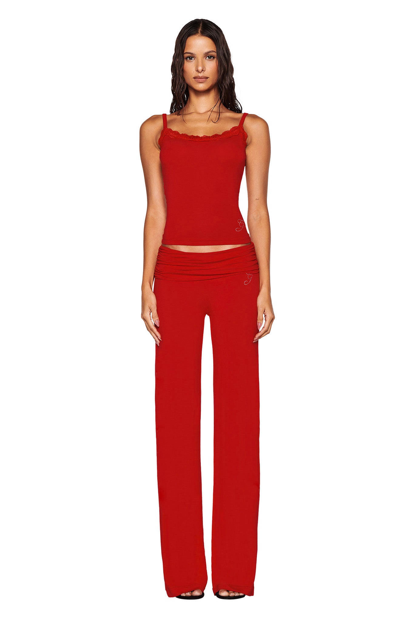 A person dressed in the fitted ERIN TOP - RED by I.AM.GIA, complete with red lace trim and coordinating red pants, stands against a simple white background, highlighting the elegance of bamboo fabrication.