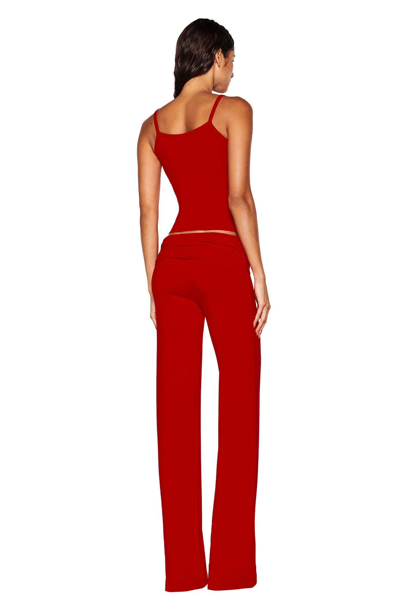 A person is facing away from the camera, dressed in a red ERIN TOP from I.AM.GIA that features delicate lace trim, paired with matching red pants. The plain white background accentuates the bamboo fabric of the outfit.
