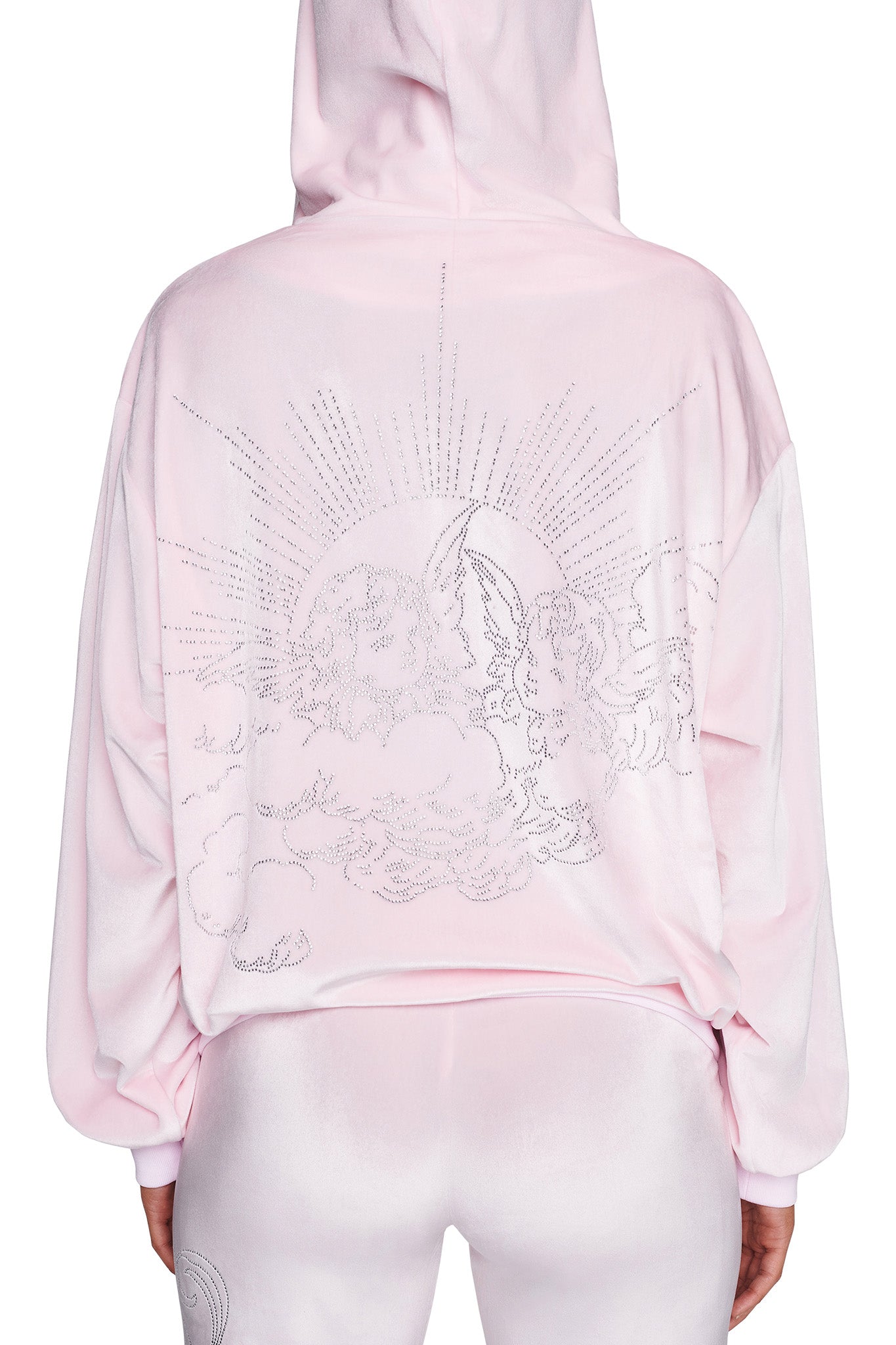 A person is shown from the back wearing the I.AM.GIA DARIA HOODIE in icy pink, with the hood up and paired with matching pants. The hoodie showcases a celestial design of clouds, a sun, and rays of light composed of small dots, creating an enchanting scene.