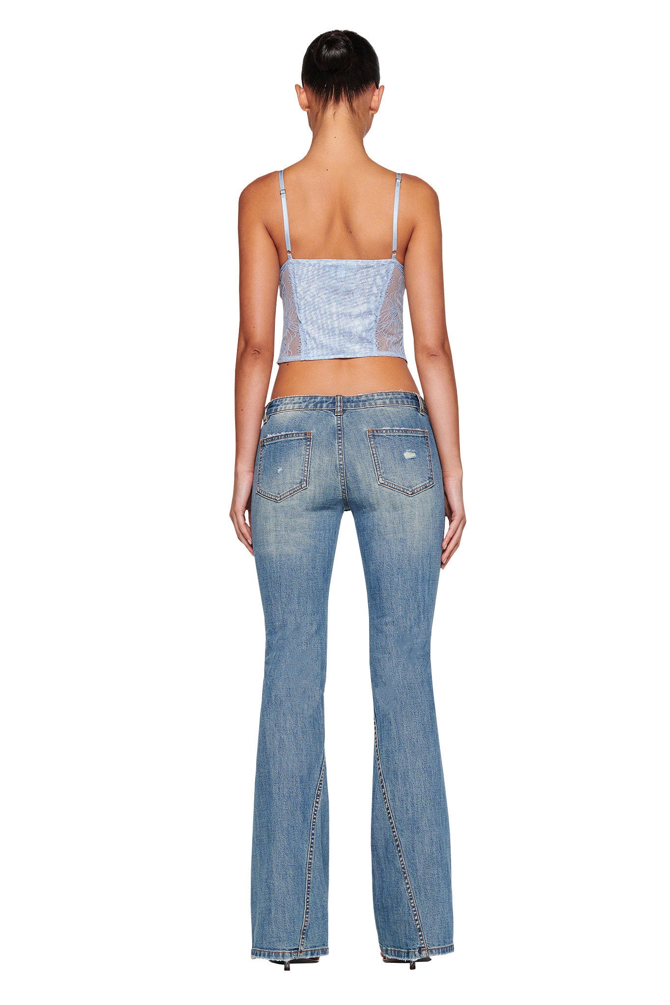 A person is shown standing with their back facing the viewer, wearing a blue and white sleeveless top from I.AM.GIA, paired with the MYLEE JEAN - BLUE from I.AM.GIA, which are light blue flared jeans adorned with rhinestones along the seams and pockets. The background is plain white.
