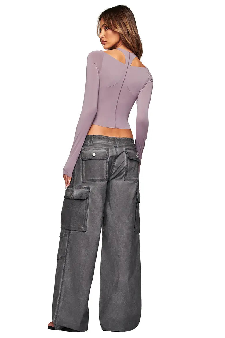 A woman faces away, wearing a mauve fitted top with back cutouts and I.AM.GIA JAXXON CARGO PANT in washed black, featuring a low-rise waist and large pockets.