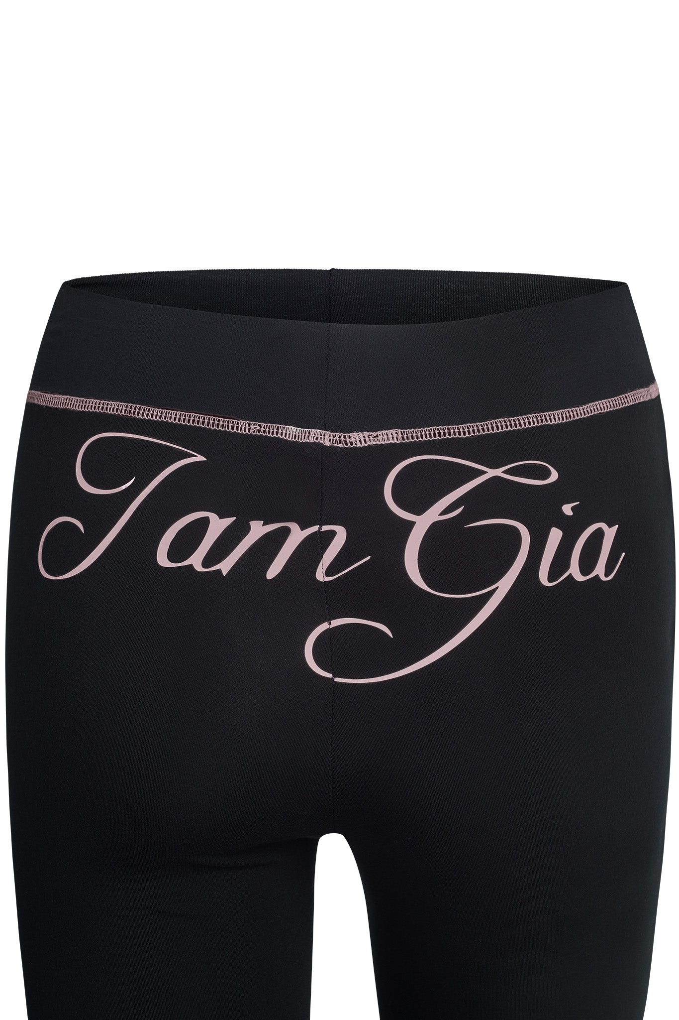 Close-up of the back of a pair of BLARE TRACKPANT - BLACK with the brand name "I.AM.GIA" written in large, cursive pink lettering across the waistband. The trackpants appear to be form-fitting and made from a smooth fabric.
